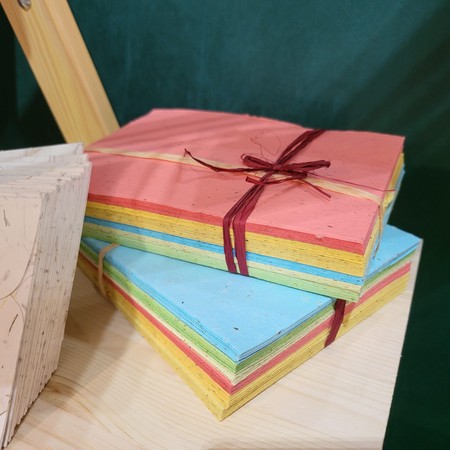 Colourful handmade paper tied with ribbon and white paper with petals
