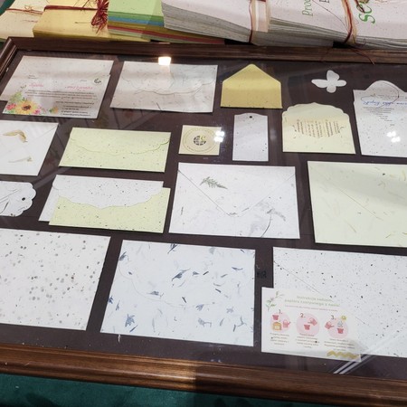 Próbki papierów czerpanych, kopert i zawieszek w gablocie na stoisku ART-PAPIER