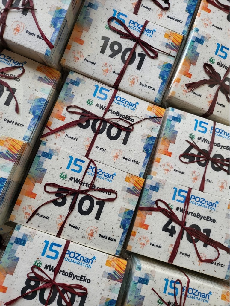 Pudełka z nadrukiem „15 lat Poznań – #WartoByćEko” z papieru z nasionami, przewiązane wstążką