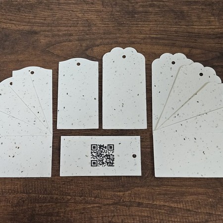 Zawieszki i metki produktowe w różnych kształtach z papieru z nasionami, jedna z kodem QR